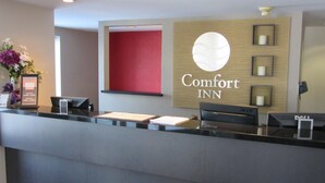 Hotellin vastaanottotiski, jossa on kyltti, jossa lukee ”Comfort INN”, ja kehystetty tervetulotoivotus.