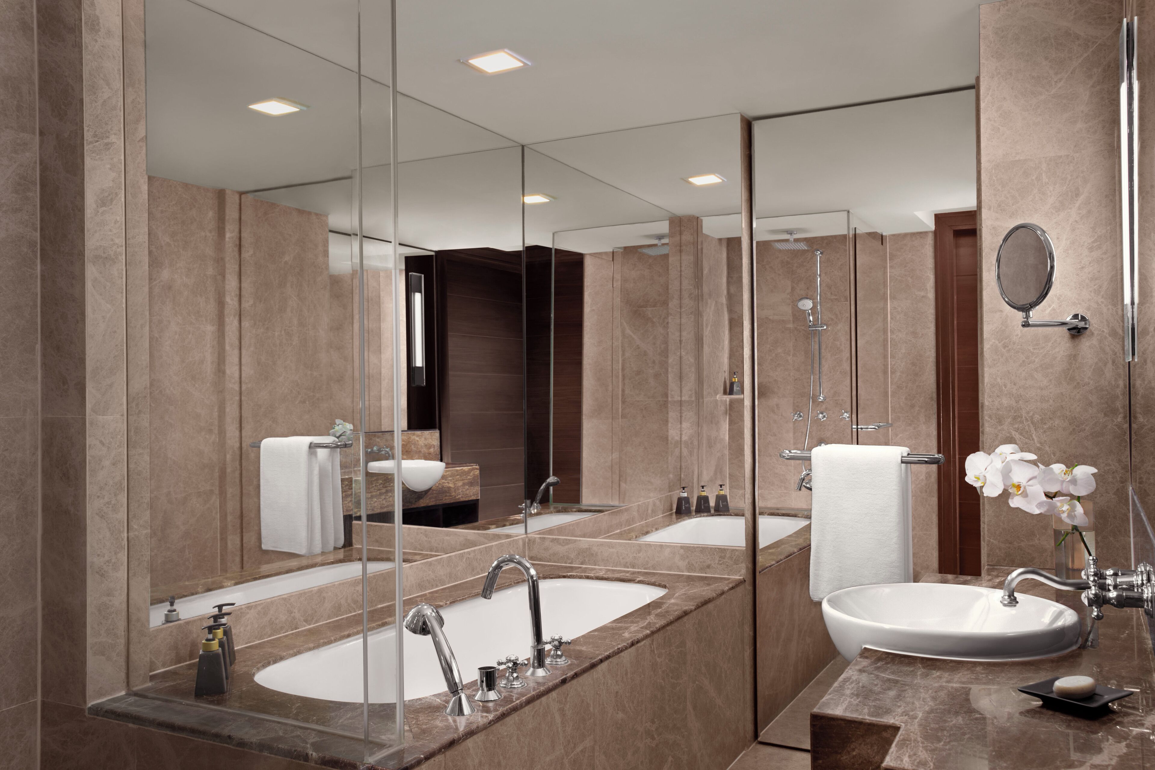 Une salle de bain moderne avec un grand miroir, deux lavabos et une douche.