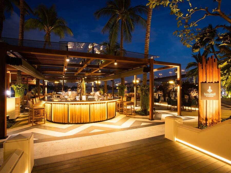 Un área de bar al aire libre con estructura de madera, asientos y un letrero que dice 'Lonotoiil by Toh'.