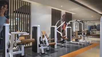 A modern gym with various exercise machines, a large mirror, and a clean, well-lit interior.