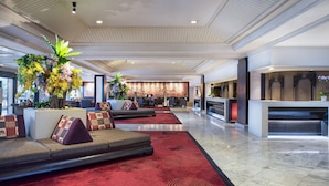 A spacious lobby with a red carpet, seating area with cushions, and a reception desk.