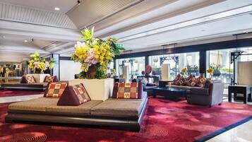 A spacious lobby with a red carpet, seating areas, and large windows.