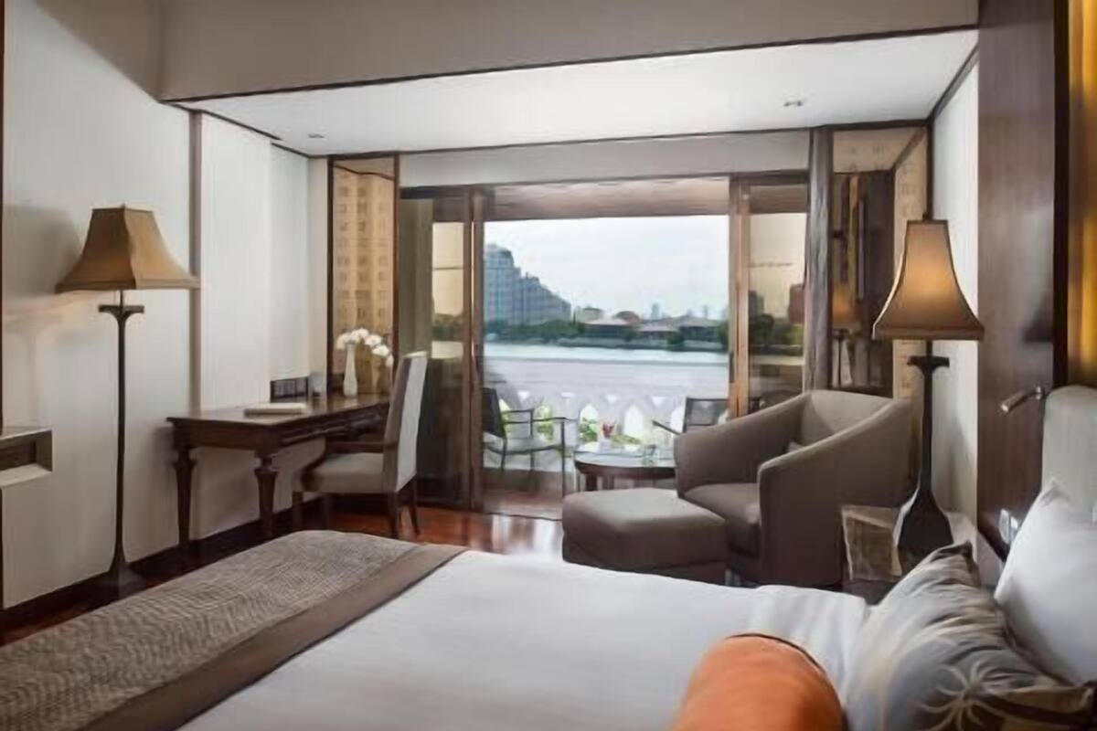 A hotel room with a bed, a desk, a chair, a table, and a view of a body of water.