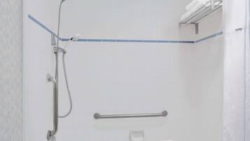 Zona de ducha con barra de apoyo, toallero y cabezal de ducha manual.