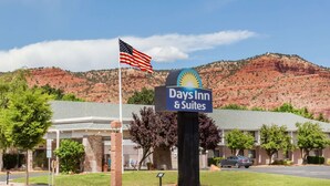 Une enseigne Days Inn & Suites, avec un drapeau américain, sur fond de paysage montagneux.