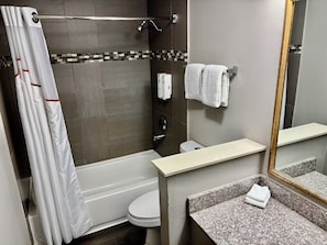 A modern bathroom with a bathtub, toilet, and shower.