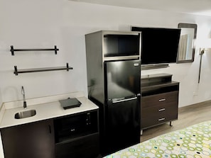 A kitchenette with a refrigerator, microwave, sink, and a small cabinet. - HomeTowne Studios by Red Roof Birmingham (Birmingham)