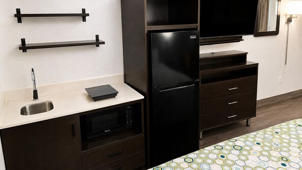 A compact kitchenette with a refrigerator, microwave, and a small sink. - HomeTowne Studios by Red Roof Birmingham - Highway 280 (Birmingham)