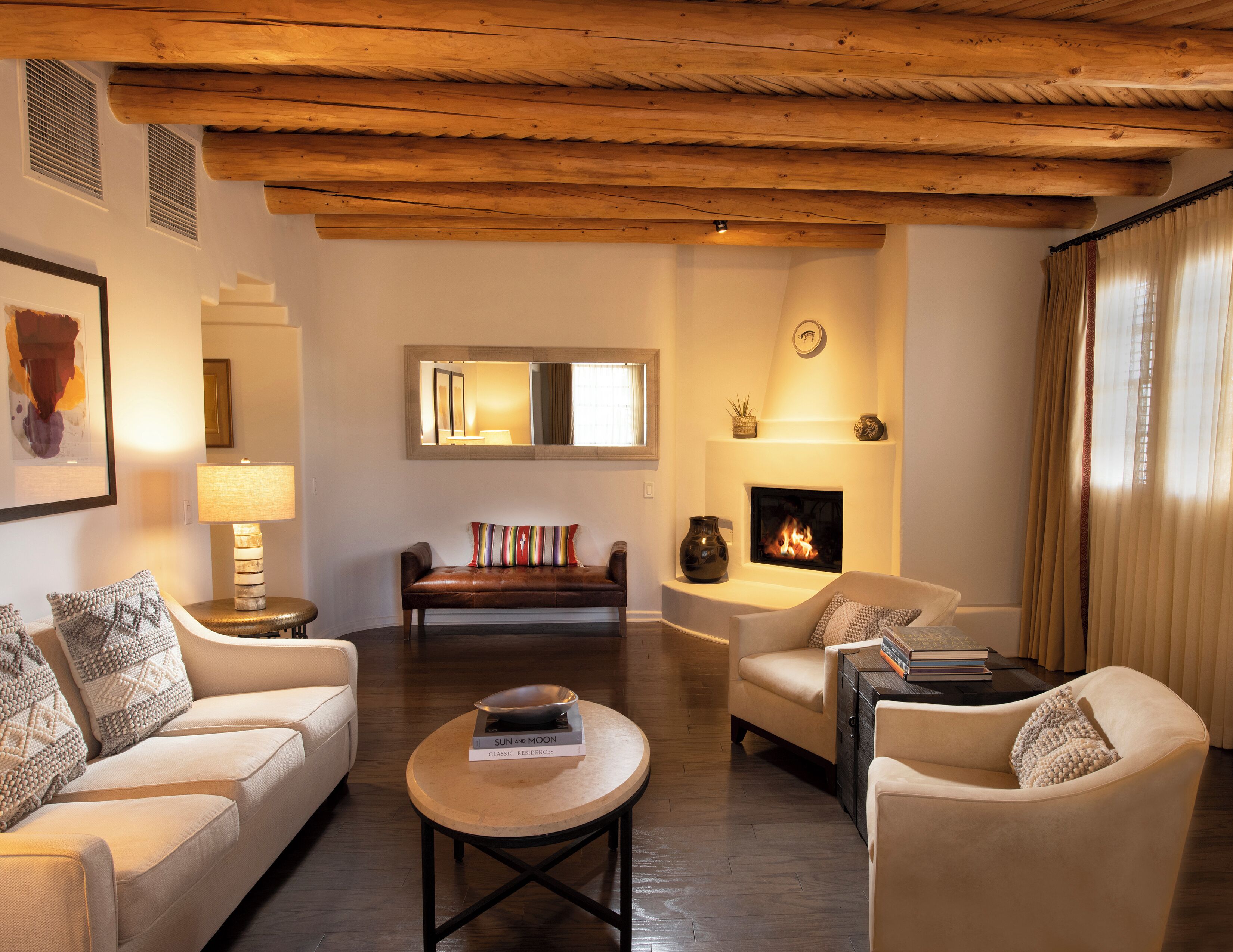 A cozy living room with a fireplace, wooden ceiling beams, and comfortable seating.