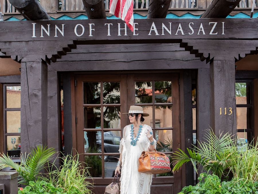 The exterior of the Inn of the Anasazi with a wooden facade, large windows, and a number '113' on the door.