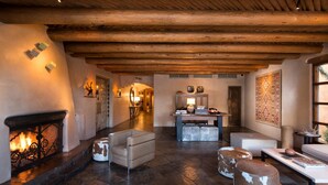Un amplio salón con chimenea, sofás de cuero y suelo de piedra.