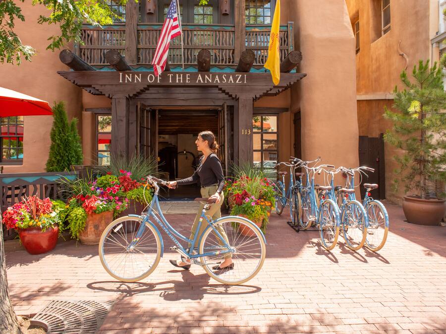 La entrada del Inn of the Anasazi con una mujer paseando en bicicleta.