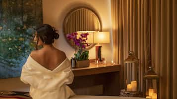 Guests can relax in a serene space with a comfortable bed, a large mirror, and a wooden nightstand with a lamp and vase.