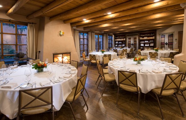 A restaurant with round tables set for dining, wooden floors, and a warm ambiance.