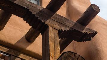 A wooden pergola structure with a window and a balcony railing.