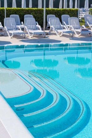 Una piscina al aire libre de temporada, sombrillas