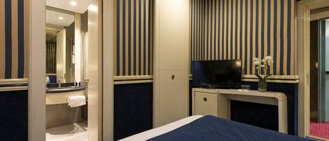 A hotel room with a bed, a TV, a desk, and a bathroom.