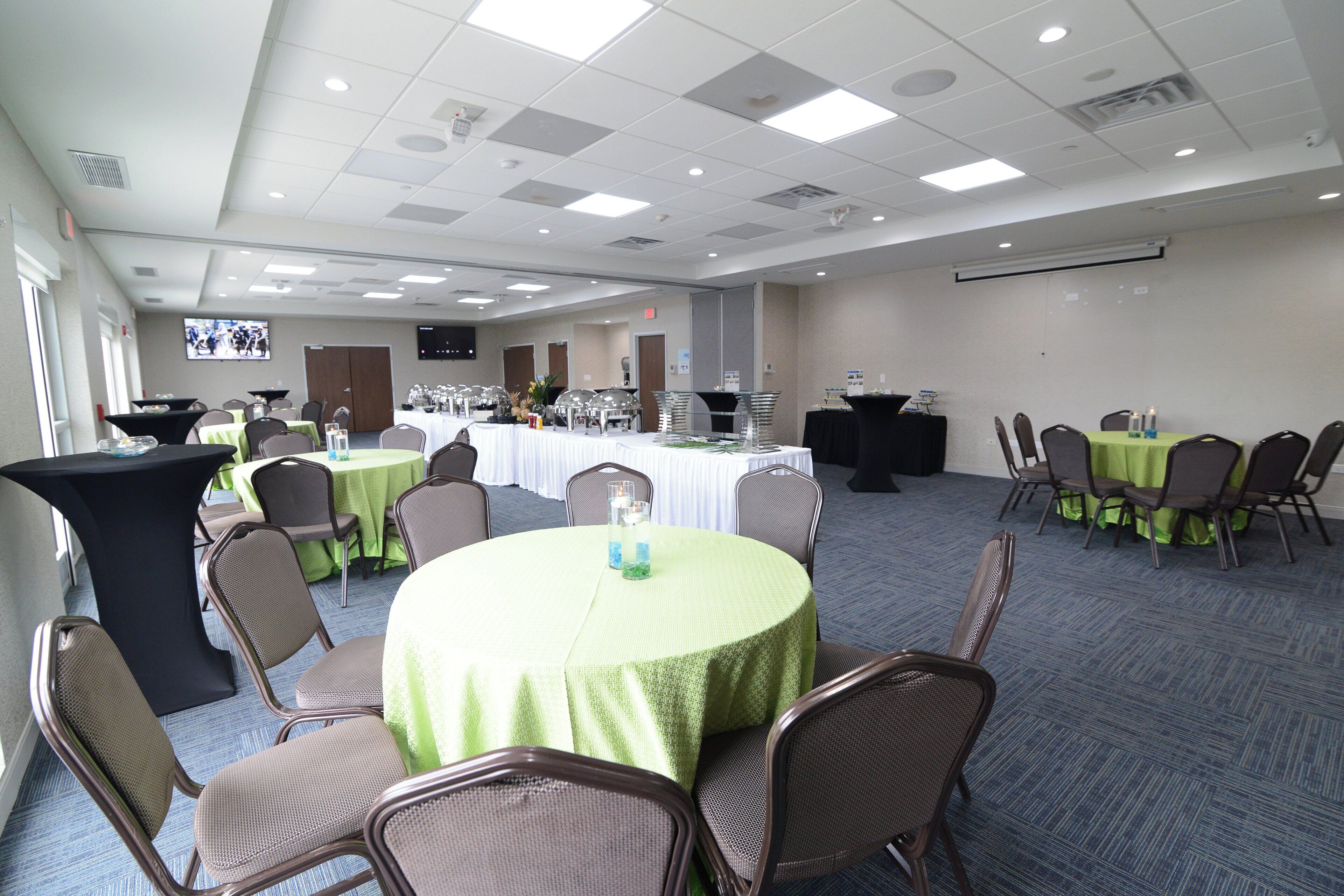 A conference room with round tables, chairs, and a television screen.