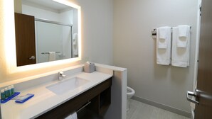 Et moderne badeværelse med et stort spejl, to vaske, et toilet og en håndklædestang.