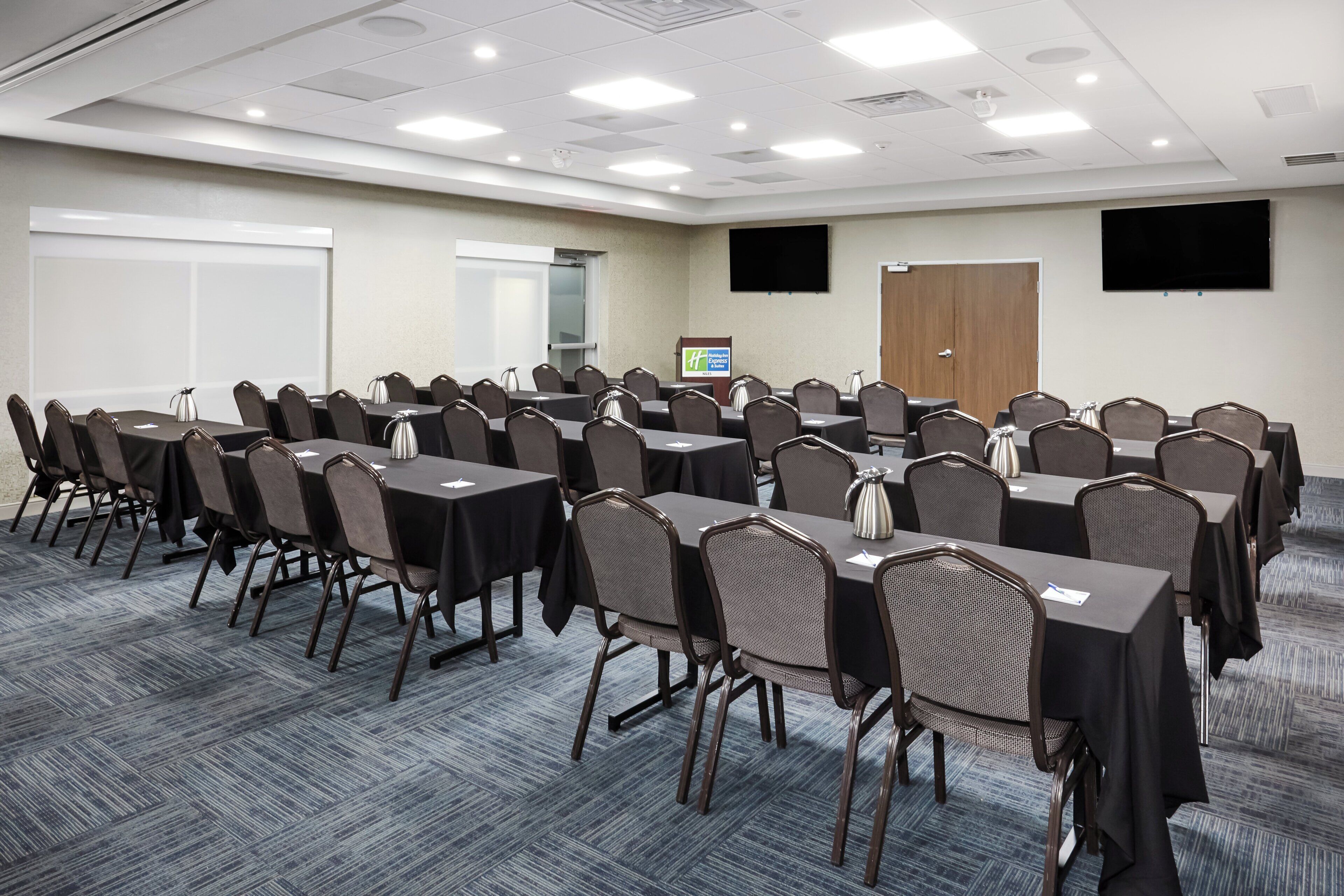 A conference room with multiple tables and chairs, equipped with nameplates and water pitchers.