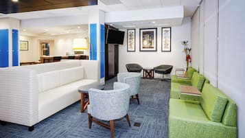 Un vestíbulo de hotel con zona de estar, una recepción y un televisor.