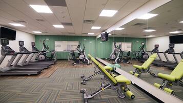 A fitness center with treadmills, elliptical machines, and a mirrored wall.