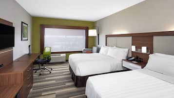 A hotel room with two beds, a desk, a chair, a TV, and a window with blinds.