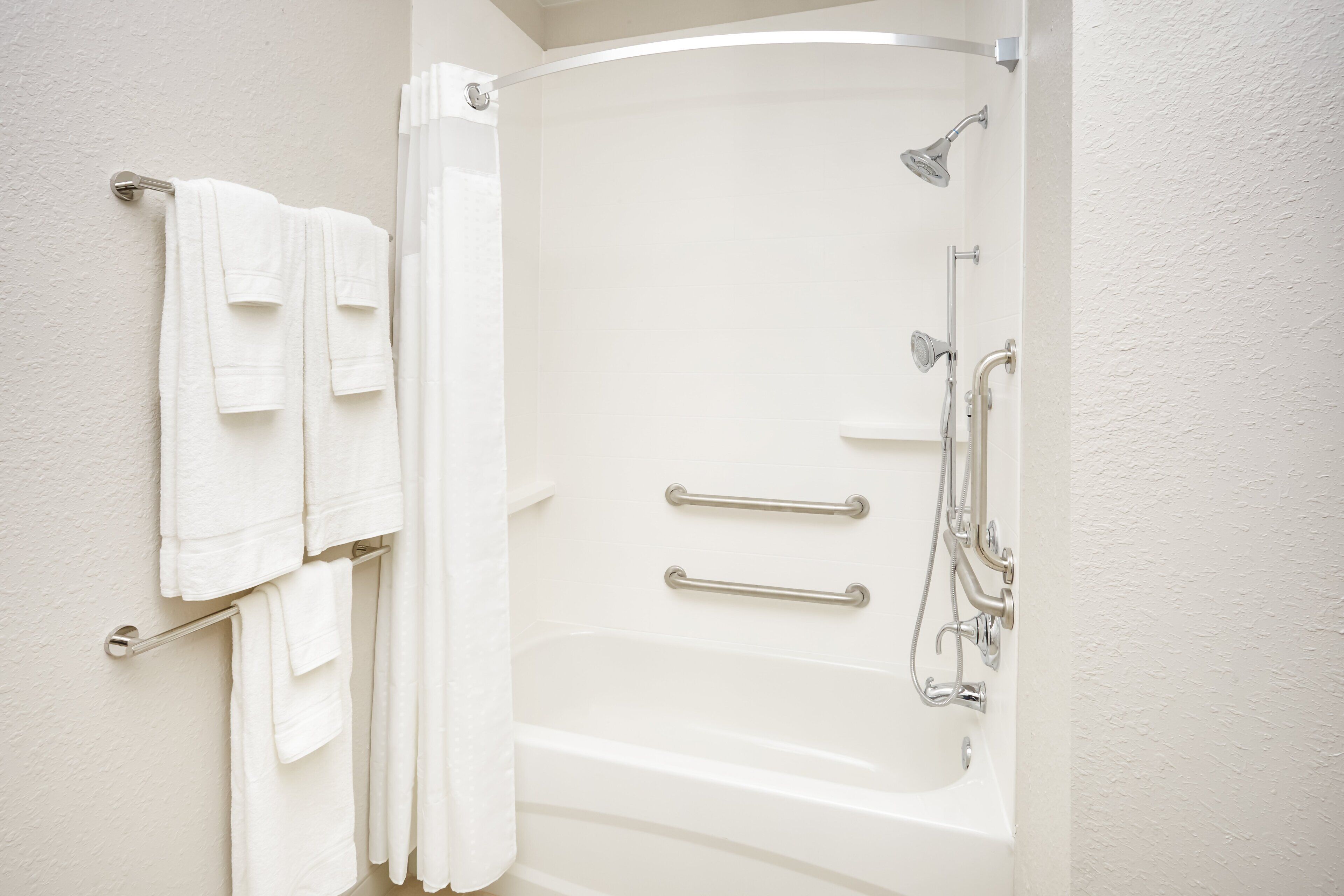 Un bagno con vasca, doccia e porta asciugamani.