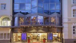 Un hôtel doté d’une façade moderne en verre, d’une tour imposante située à l’angle et d’une entrée bien éclairée.
