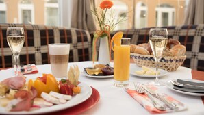 Une table dressée pour le petit-déjeuner, avec une variété d’aliments, de boissons et un panier de pain.
