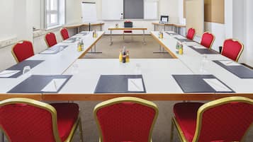 A conference room with a long table, red chairs, and a whiteboard.