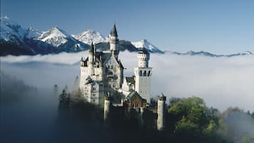 Un castillo rodeado de montañas y niebla.