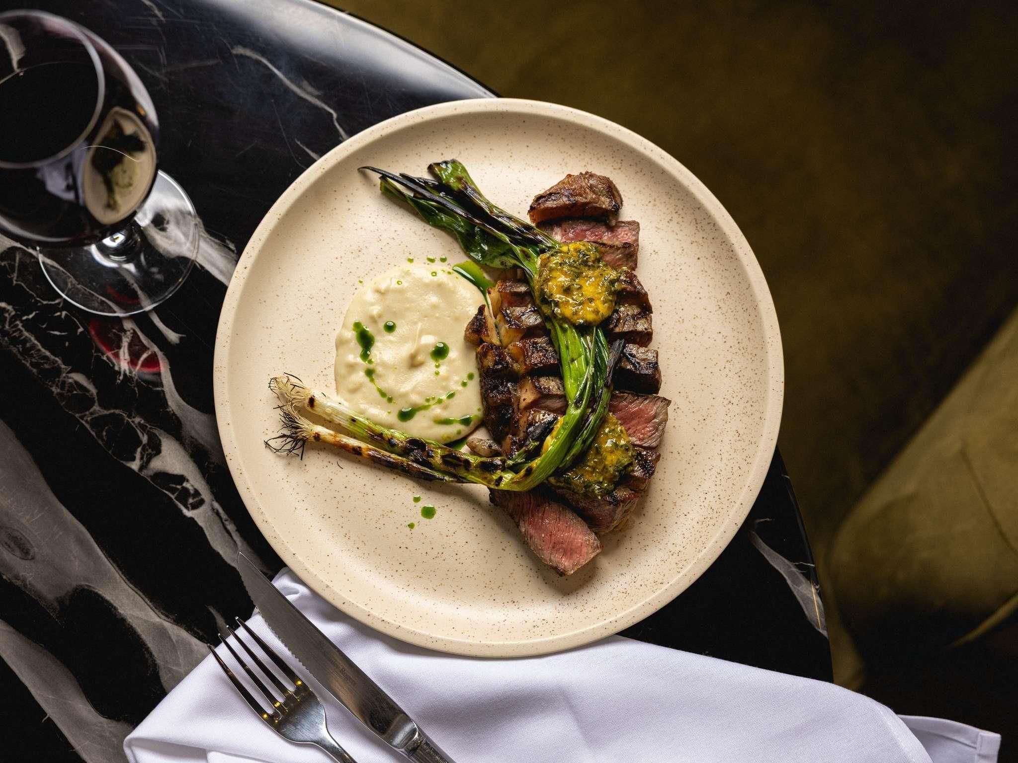 A plate of food with a glass of red wine and a fork on a table.