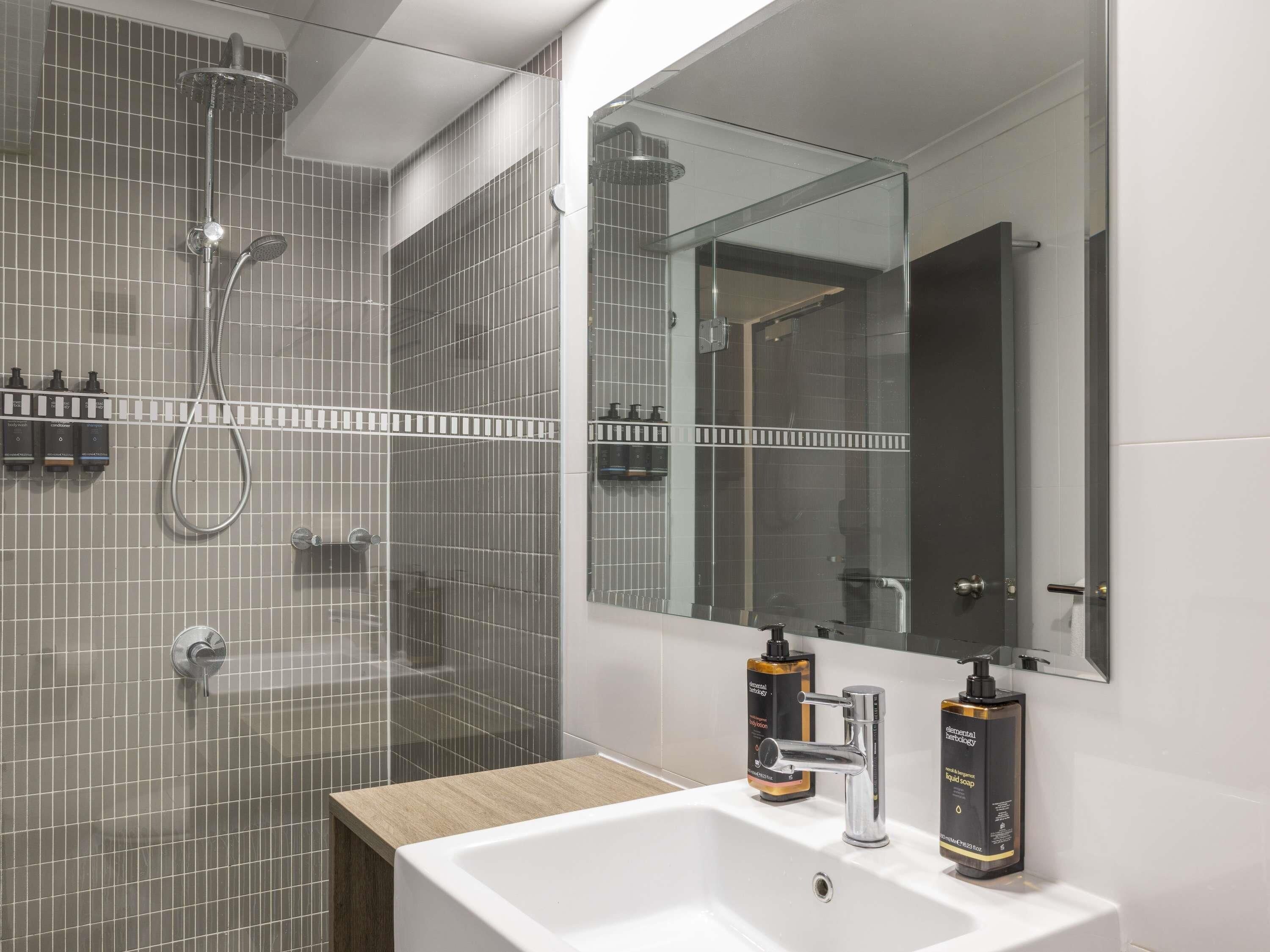 Une salle de bain moderne avec une douche, un lavabo et un grand miroir.