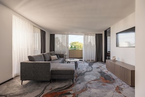 A modern hotel room with a grey sofa, a small round table, and a cabinet.