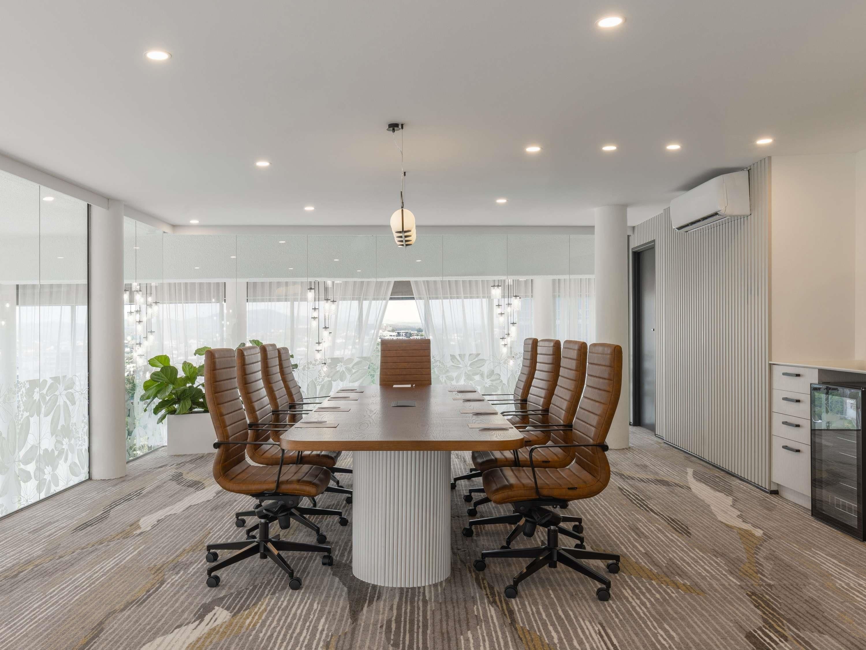 Un salón de conferencias con una mesa grande, seis sillas y una lámpara de techo moderna.