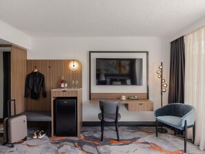 A hotel room with a desk, chair, minibar, and a TV mounted on the wall. - Mercure Brisbane Spring Hill (Spring Hill)