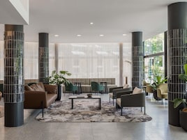 Un vestíbulo amplio con zona de estar central, ventanas grandes y pilares decorativos.