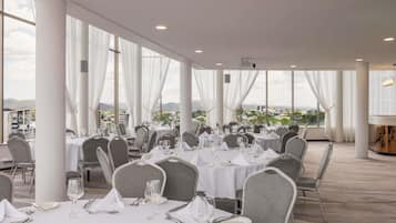 A spacious indoor dining area with round tables, white tablecloths, and grey chairs.
