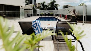 A poolside area with a table, chairs, and a towel. - Mercure Brisbane Spring Hill (Spring Hill)