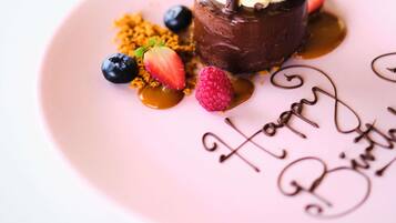 A dessert on a pink plate with 'Happy Birthday' written on it.