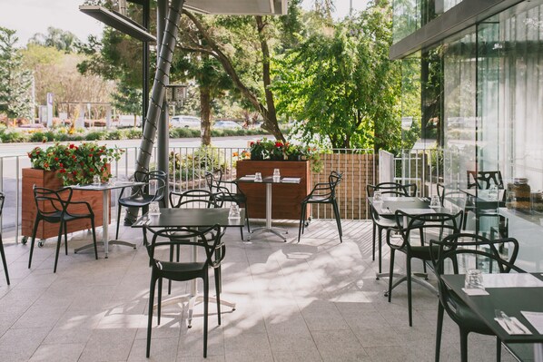 Enjoy al fresco dining in a serene outdoor setting surrounded by lush greenery and comfortable seating.