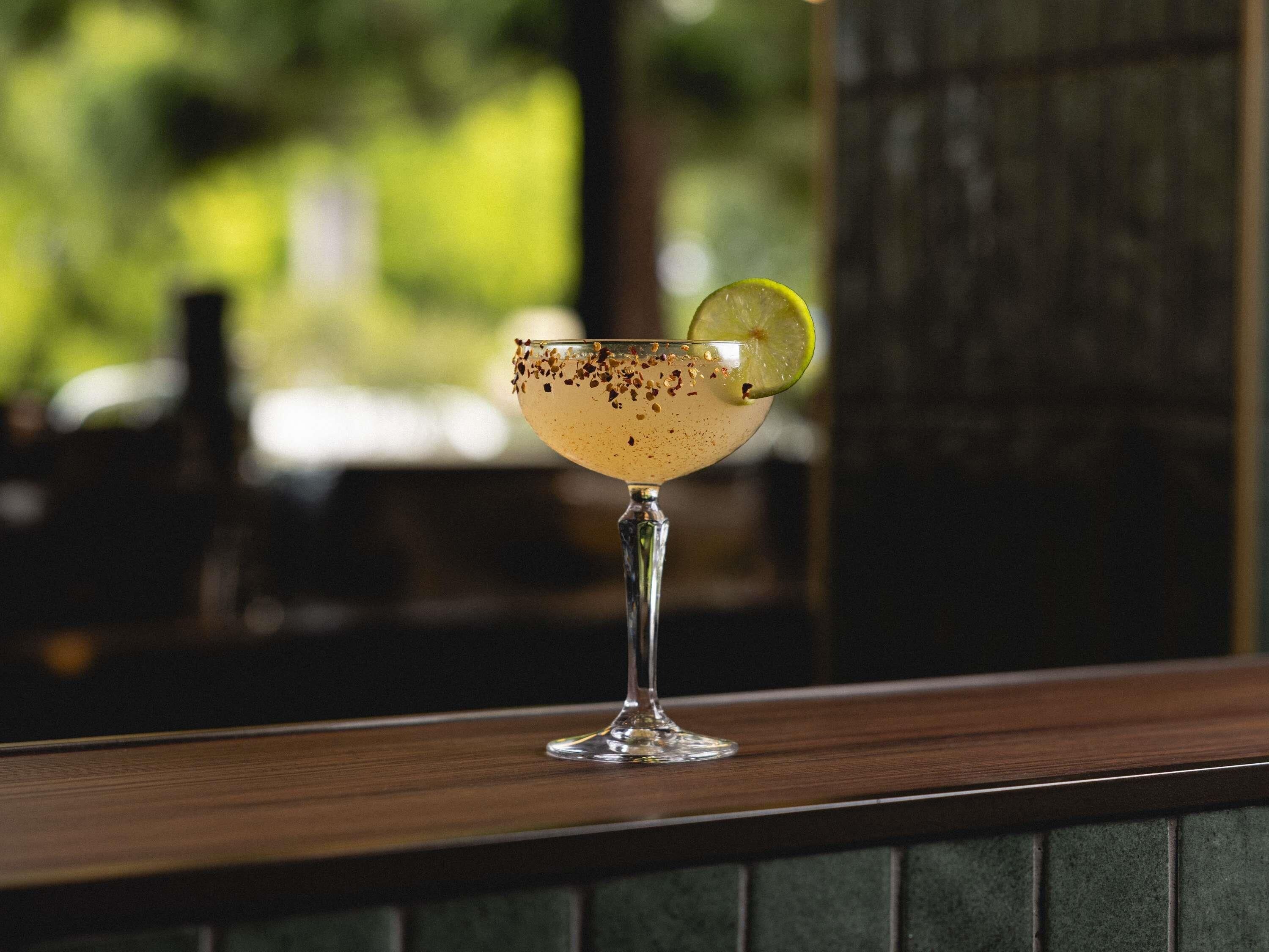A cocktail glass with a lime garnish on a bar counter.