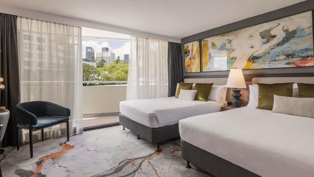 A hotel room with two beds, a chair, a desk, a painting, and a view of the cityscape. - Mercure Brisbane Spring Hill (Spring Hill)