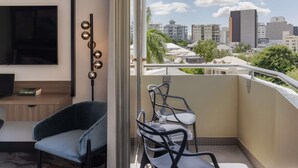 Un balcón con vista a la ciudad, un televisor, una silla y una mesa.
