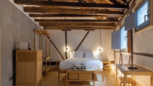 A bedroom with a wooden bed, bedside tables, a desk, and a TV. - Hotel Carlos V (Toledo)