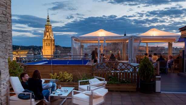 An outdoor patio with seating, a view of a historic tower, and a gazebo. - Hotel Carlos V (Toledo)