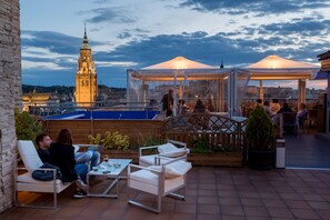 An outdoor patio with seating, a view of a historic tower, and a gazebo. - Hotel Carlos V (Toledo)