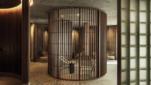 A modern interior with a curved wooden partition, a staircase, and a seating area with upholstered chairs. - Hagastrand, Autograph Collection (Solna)