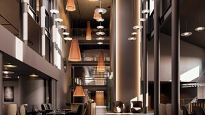 A spacious lobby with multiple seating areas, a central staircase, and modern pendant lighting. - Hagastrand, Autograph Collection (Solna)